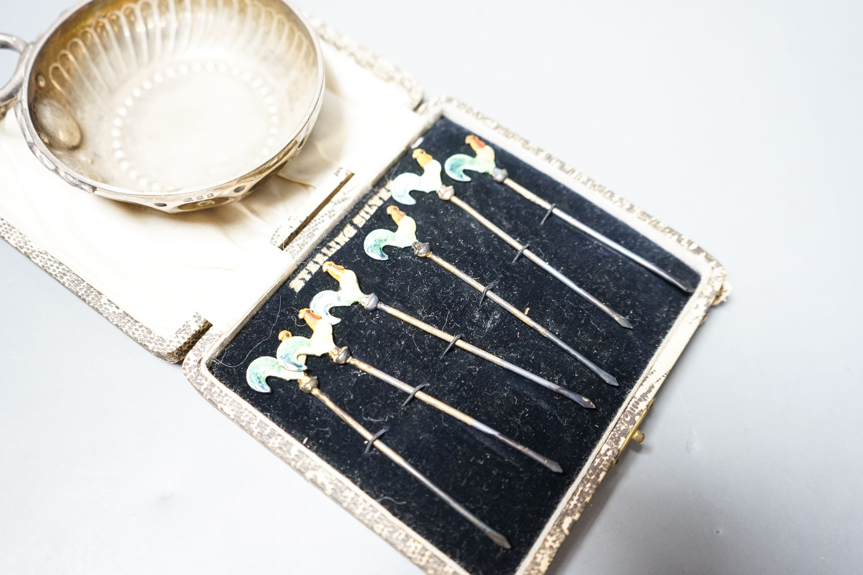 A 1930's silver taste vin and a cased set of six sterling and enamel cocktail sticks.